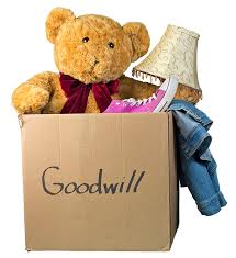 Box of donations to Goodwill including teddy bear, lamp and pink shoes.