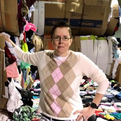 Jenny Crabtree, salvage manager, standing infront of bails of clothing. 