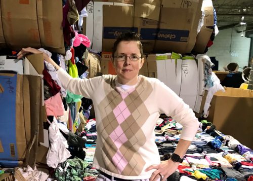 Jenny Crabtree, salvage manager, standing infront of bails of clothing.